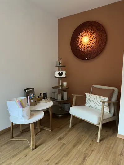 Ecke im Studio mit weissem Sessel, Beistelltisch und runder Wandleuchte