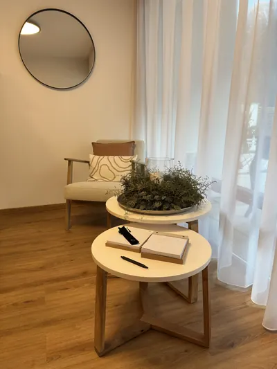 Sitzecke im Studio mit Sessel, rundem Tisch und Spiegel